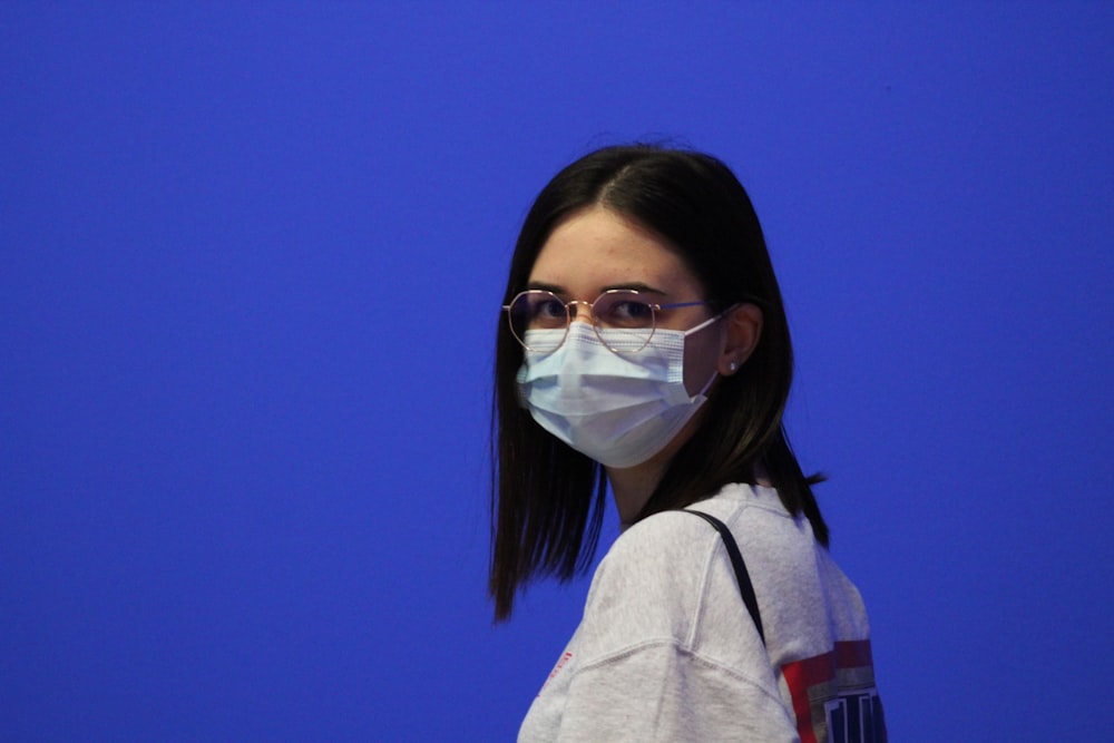 a woman wearing a face mask against a blue background