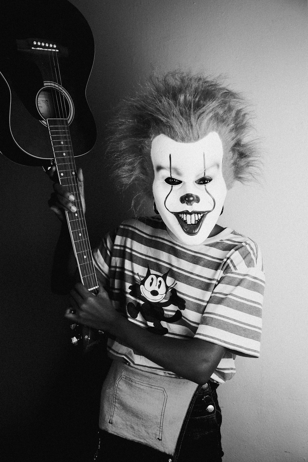 a young boy with a clown makeup holding a guitar