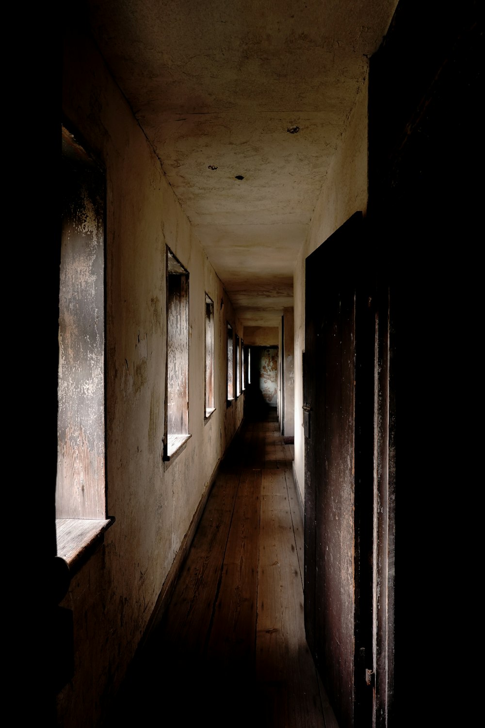 a long hallway with wooden floors and windows