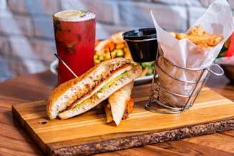 a sandwich on a cutting board next to a drink