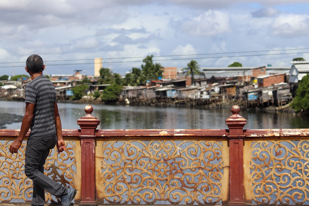 a man walking across a bridge over a river