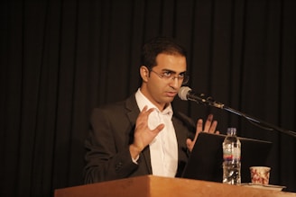 a man in a suit and tie speaking into a microphone