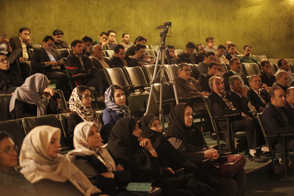 Large auditorium filled with people seated in rows facing the front of the room