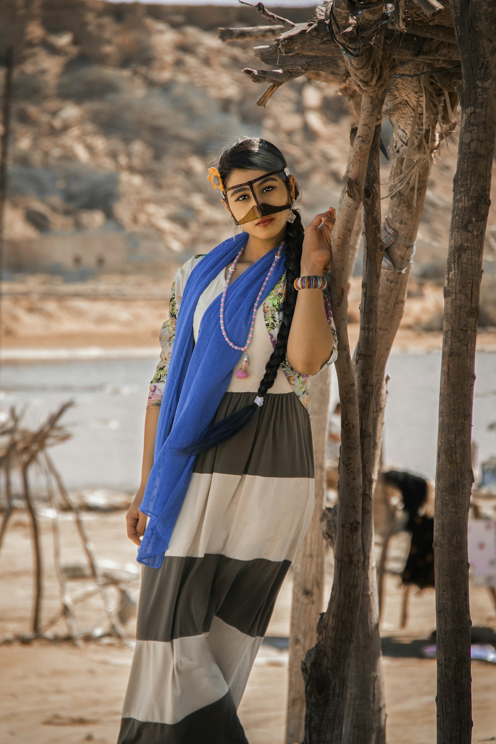 a woman standing next to a tree wearing a blue scarf