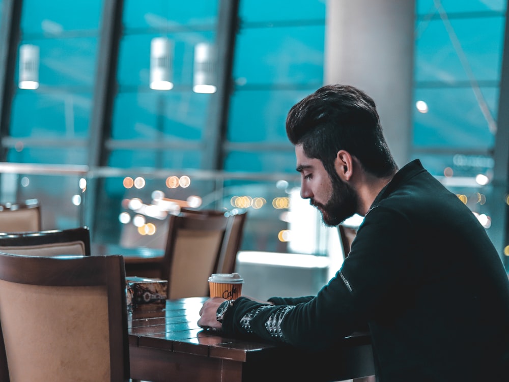 a man sitting at a table with a cup of coffee