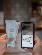 A hand holding several packaged chocolate bars is visible on the left, while another hand holds a smartphone displaying information about 'Pure Heavenly' chocolate bars with an option to open a link.