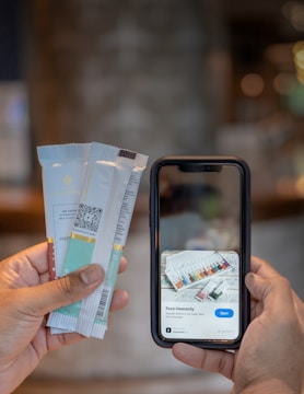 A hand holding several packaged chocolate bars is visible on the left, while another hand holds a smartphone displaying information about 'Pure Heavenly' chocolate bars with an option to open a link.