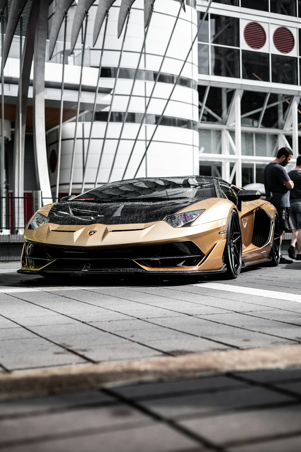a gold and black sports car parked in front of a building