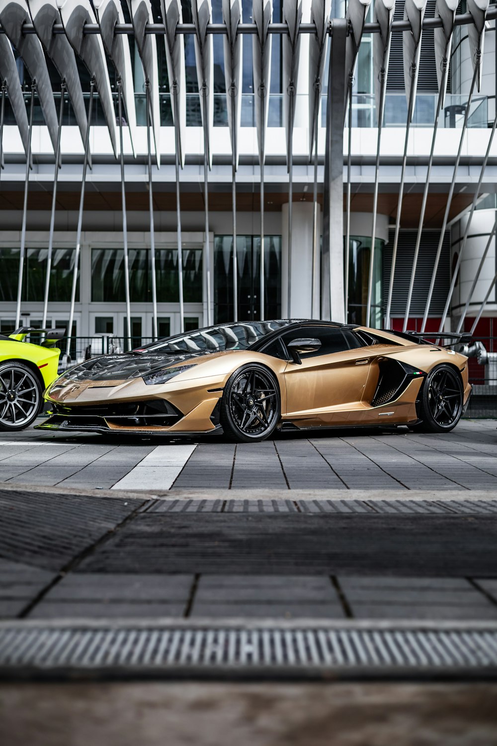 a gold colored sports car parked in front of a building