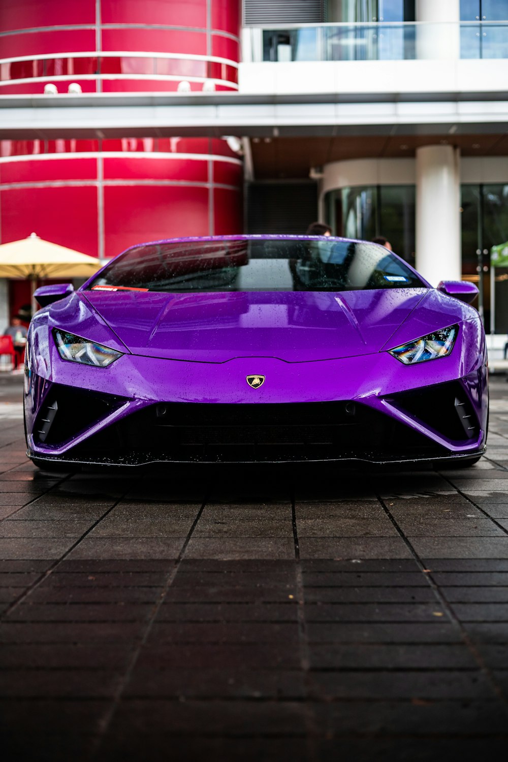 a purple sports car parked in front of a building