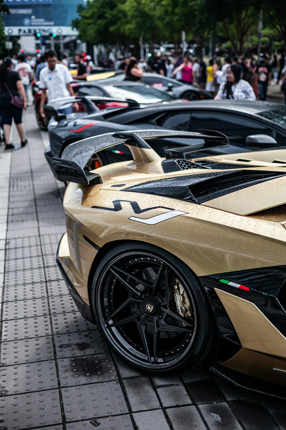 a row of gold sports cars parked on the side of a street