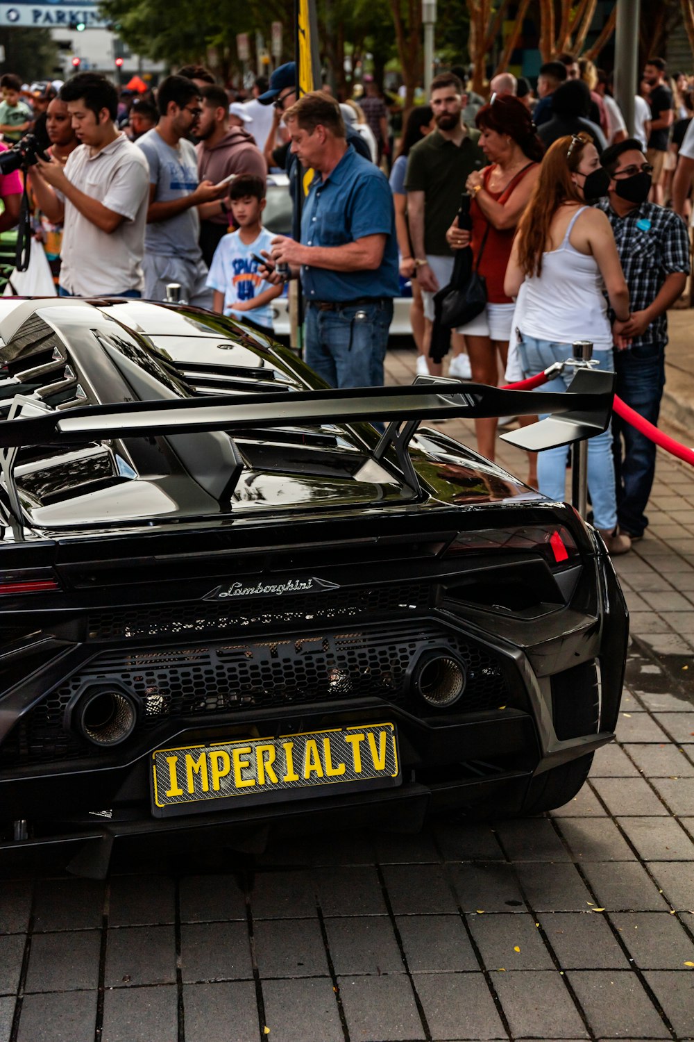 a black sports car parked in front of a crowd of people