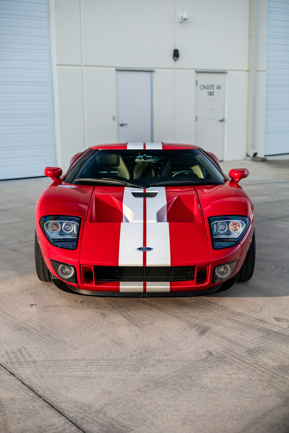 a red and white sports car parked in front of a garage