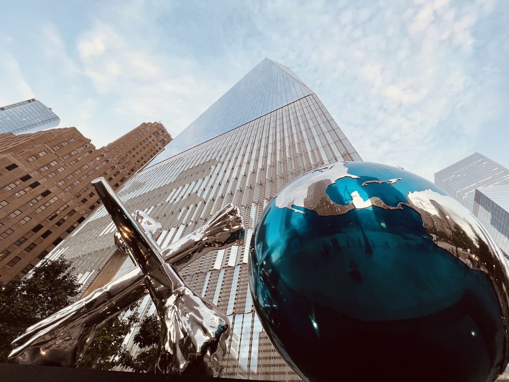 a large metal ball sitting in front of a tall building