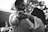 A couple gazes into each other's eyes while holding hands with the focus on an engagement ring. The image is in black and white, providing a timeless and intimate feel.