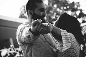 A couple gazes into each other's eyes while holding hands with the focus on an engagement ring. The image is in black and white, providing a timeless and intimate feel.