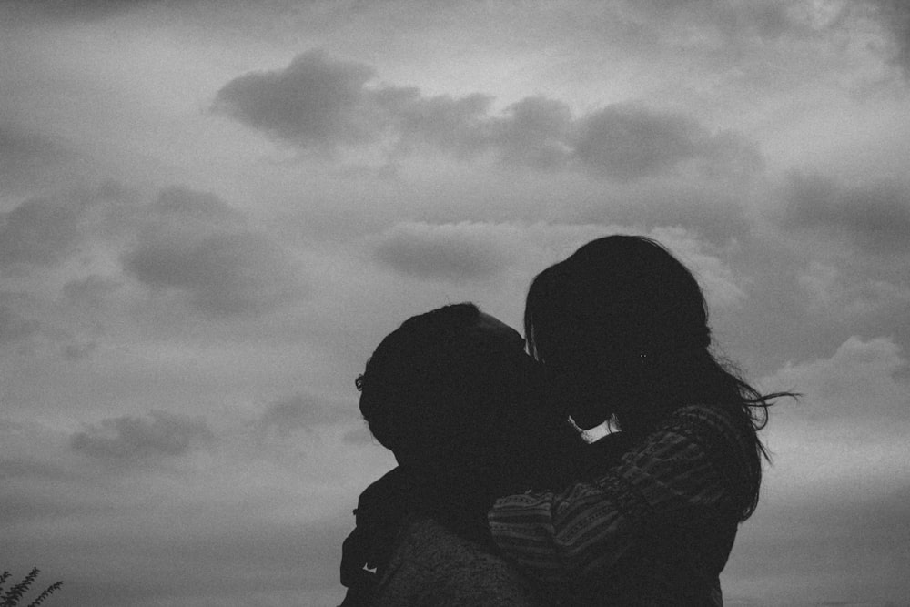 a couple of people standing next to each other under a cloudy sky