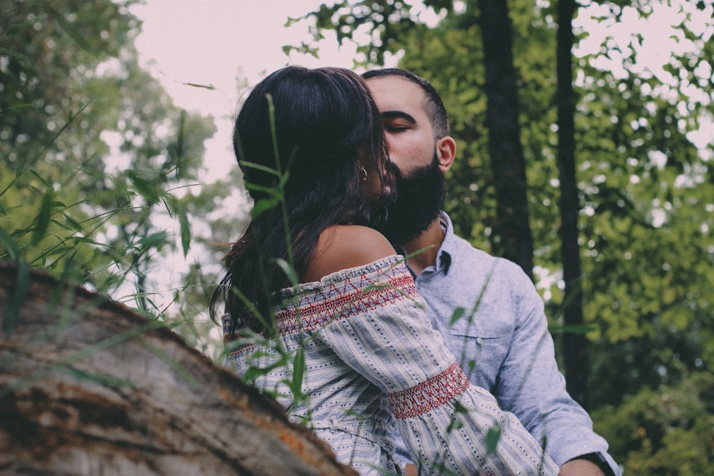 a man and a woman kissing in the woods