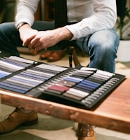 a man sitting at a table with a display of ties on it