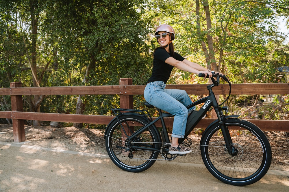Una mujer con camisa negra montando una bicicleta negra