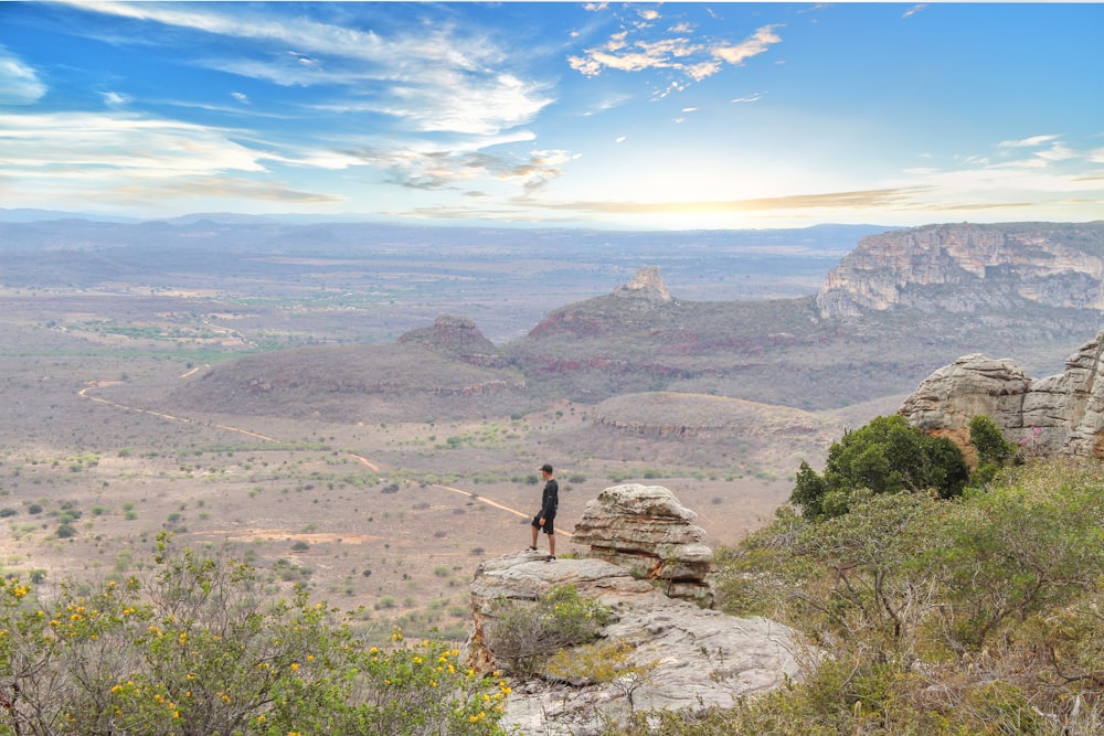 a person standing on top of a cliff overlooking a valley