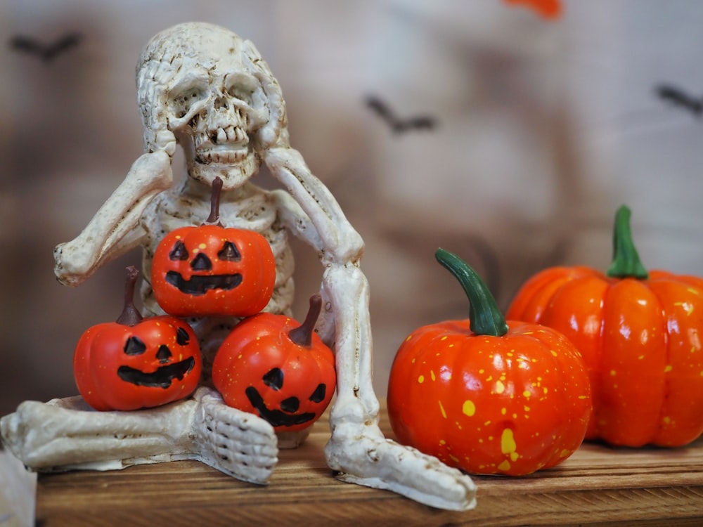 a skeleton sitting on a table with pumpkins