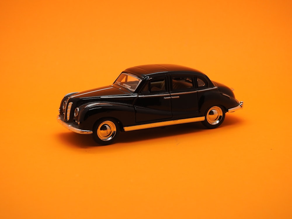 a black toy car on an orange background