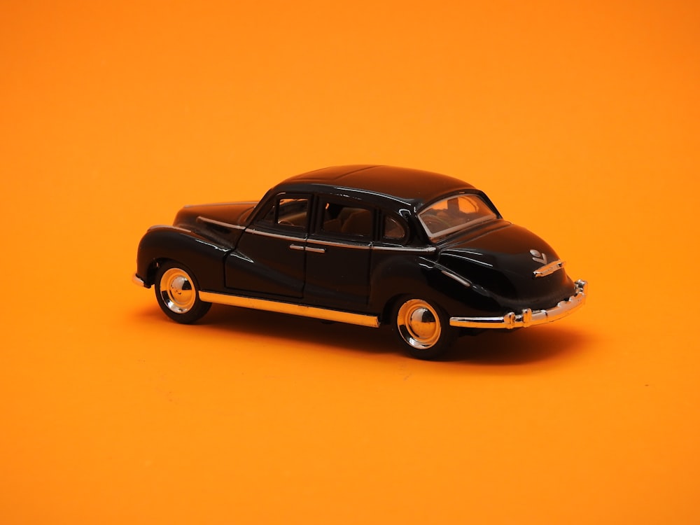 a black toy car on an orange background