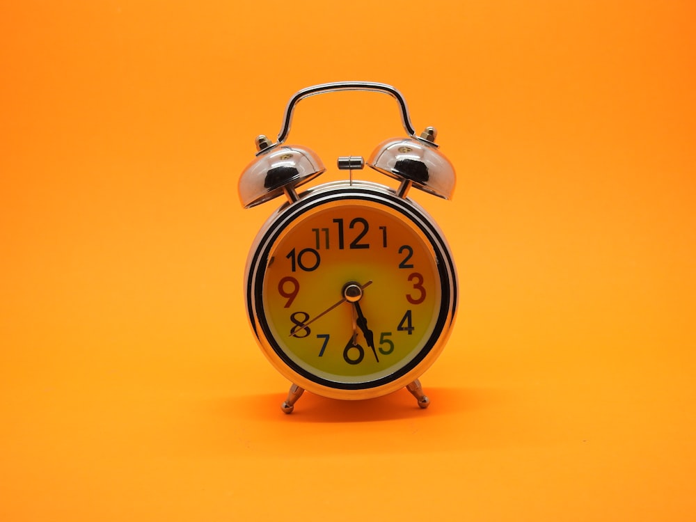 a small alarm clock on an orange background