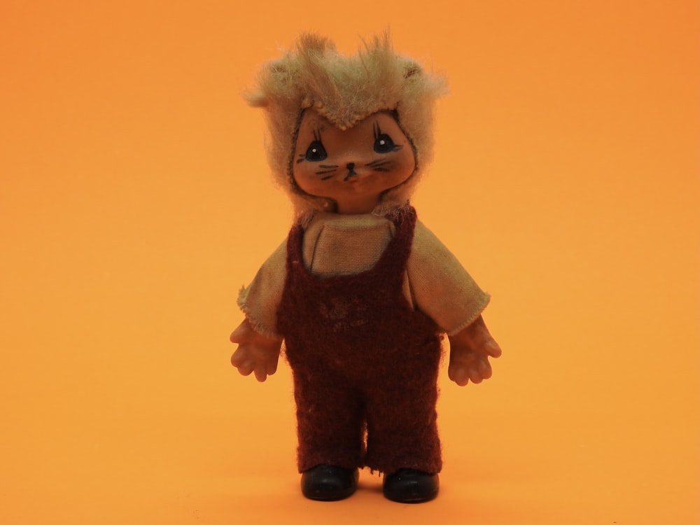 a small doll with a furry haircut and overalls
