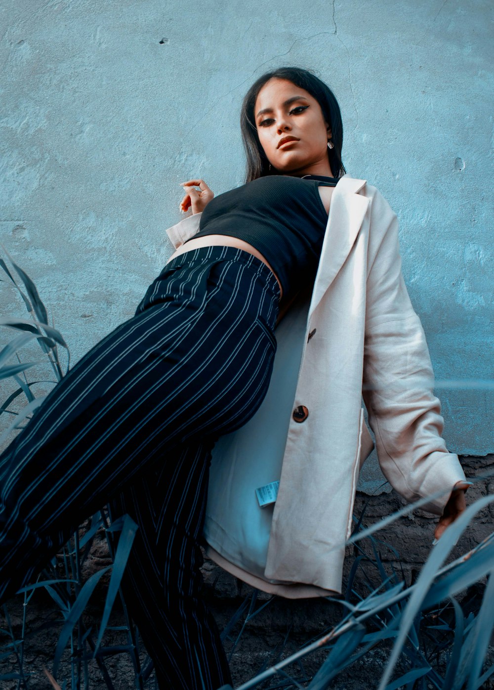 a woman leaning against a wall wearing a coat