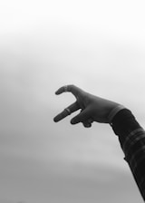 a black and white photo of a person's hand making a heart