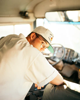 a man wearing a hat and glasses sitting in a bus