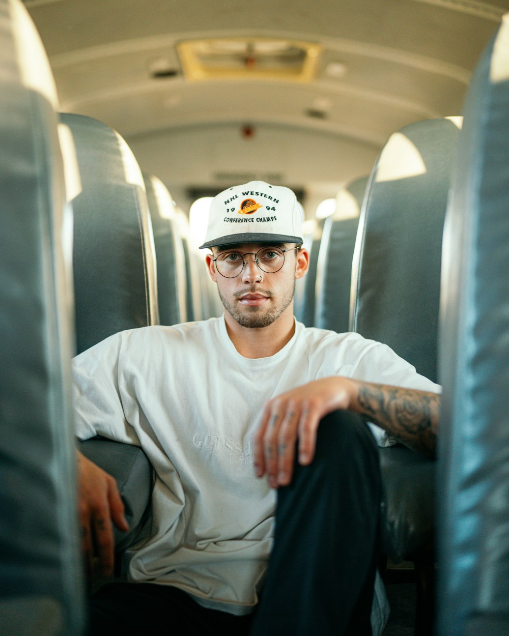 a man with a hat and glasses sitting on a bus