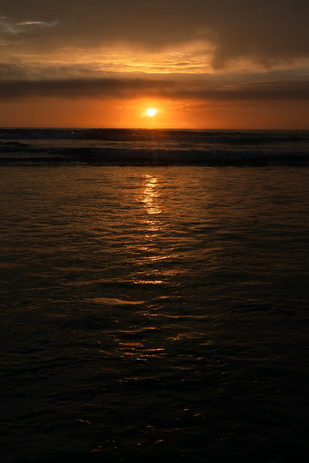 the sun is setting over the ocean on a cloudy day