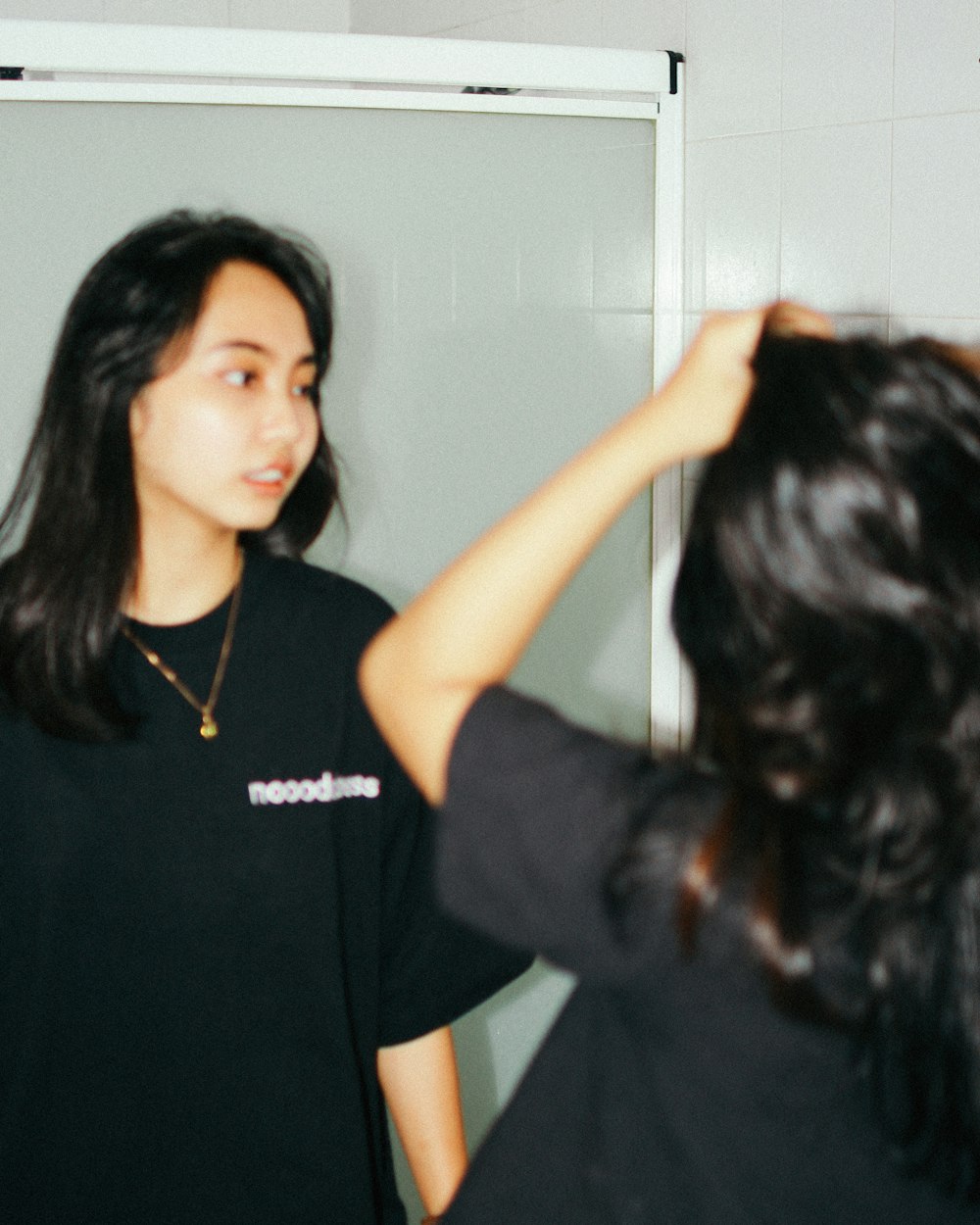 a woman standing in front of a mirror brushing her hair