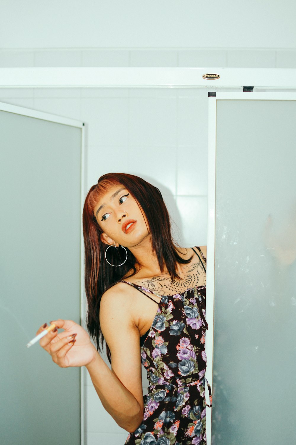 a woman in a floral dress smoking a cigarette