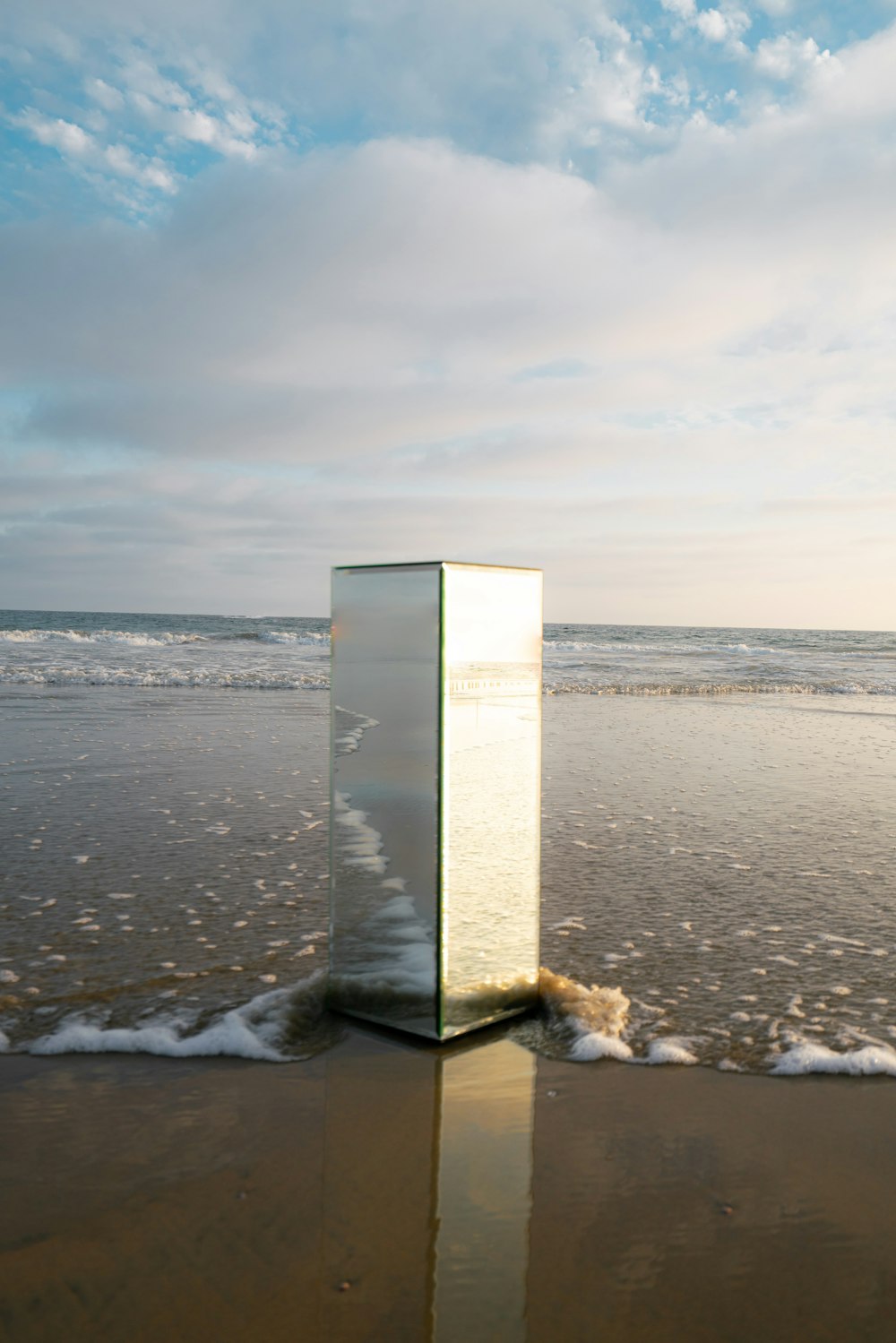 a glass cube sitting on top of a sandy beach