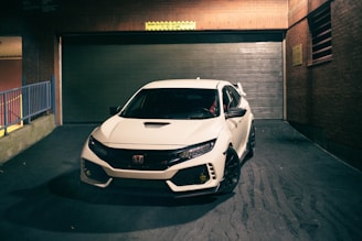 a white car parked in front of a garage