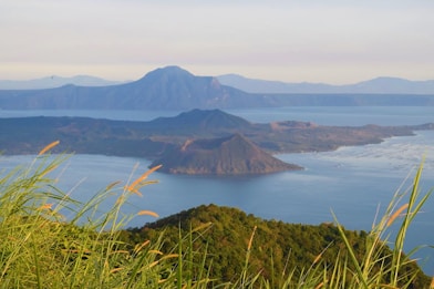 a view of a lake and mountains from the top of a hill
