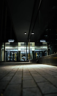 A sleek, dark-themed office lobby entrance at 26 Magrath Road with subtle lighting.
