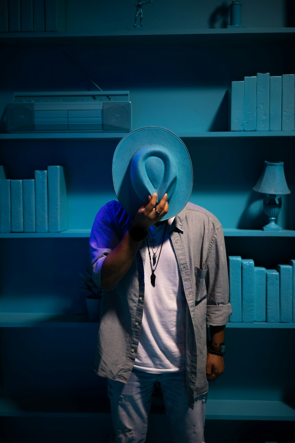 a man wearing a blue hat standing in front of a book shelf