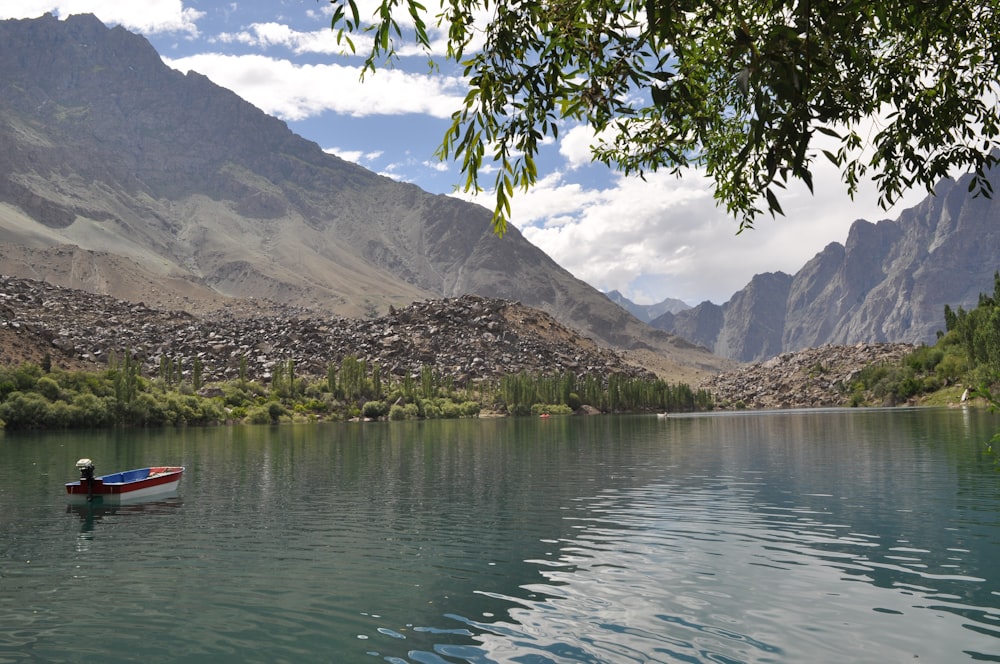 a small boat floating on top of a lake surrounded by mountains