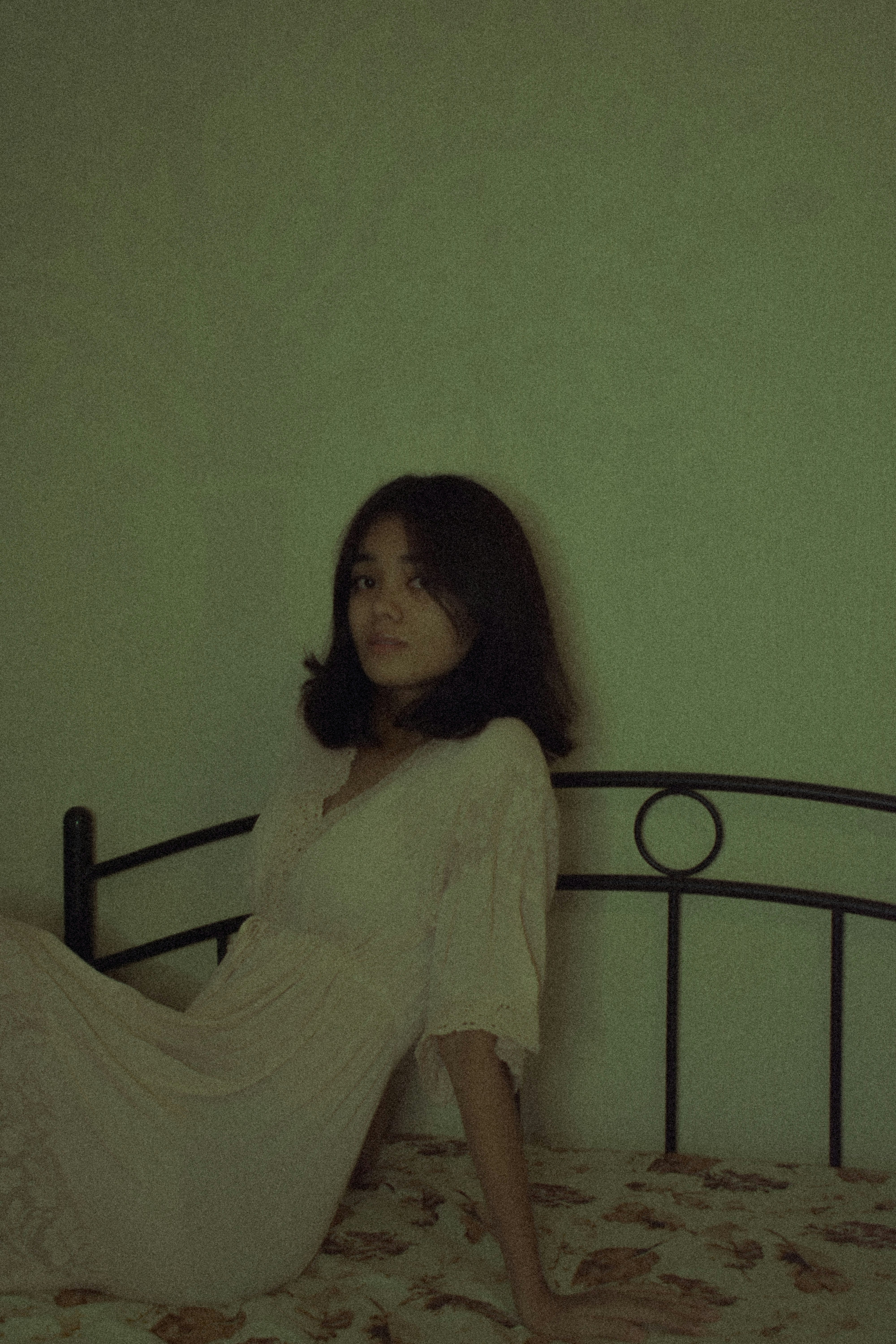 a woman sitting on a bed in a white dress