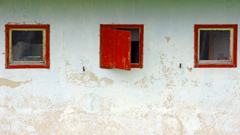 a red window on a white wall with three windows