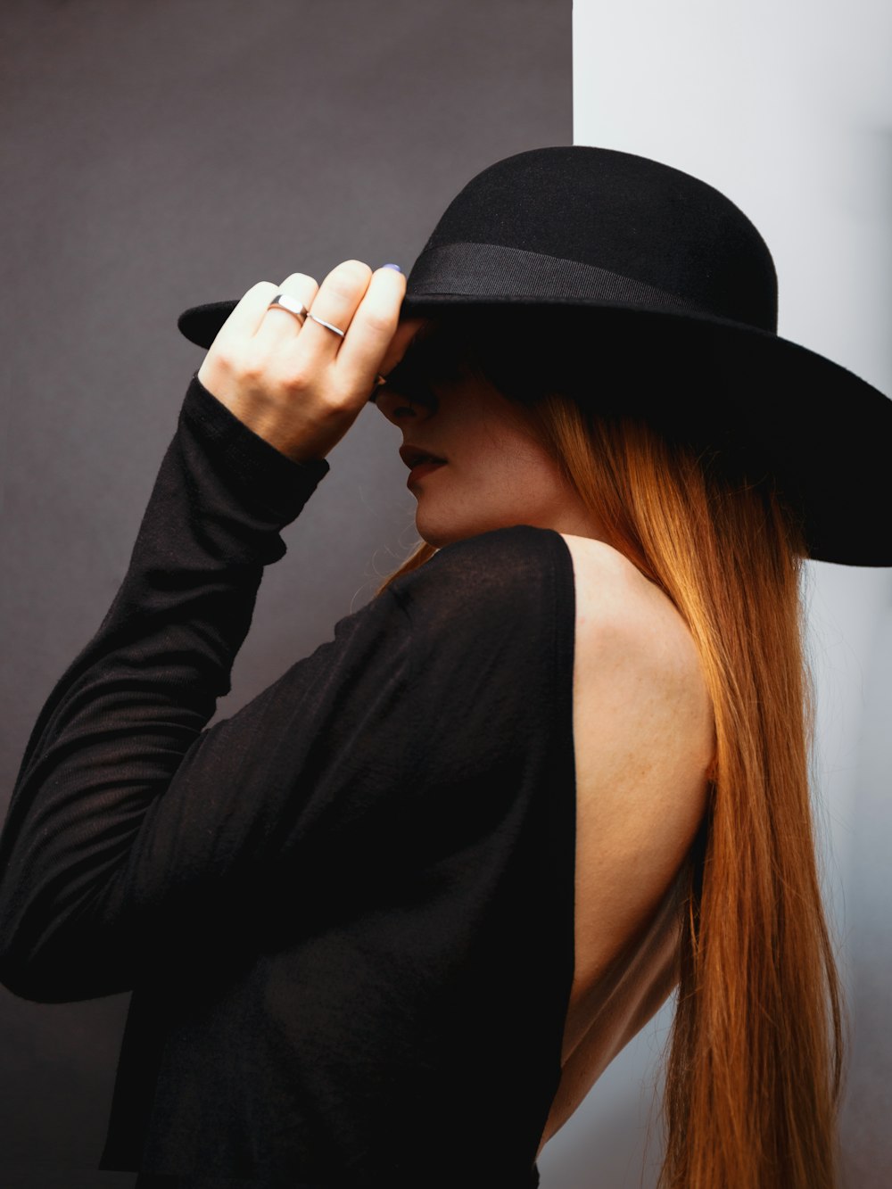 a woman with long red hair wearing a black hat