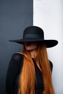 a woman with long red hair wearing a black hat