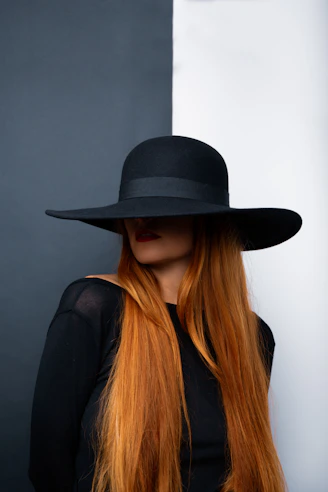 a woman with long red hair wearing a black hat
