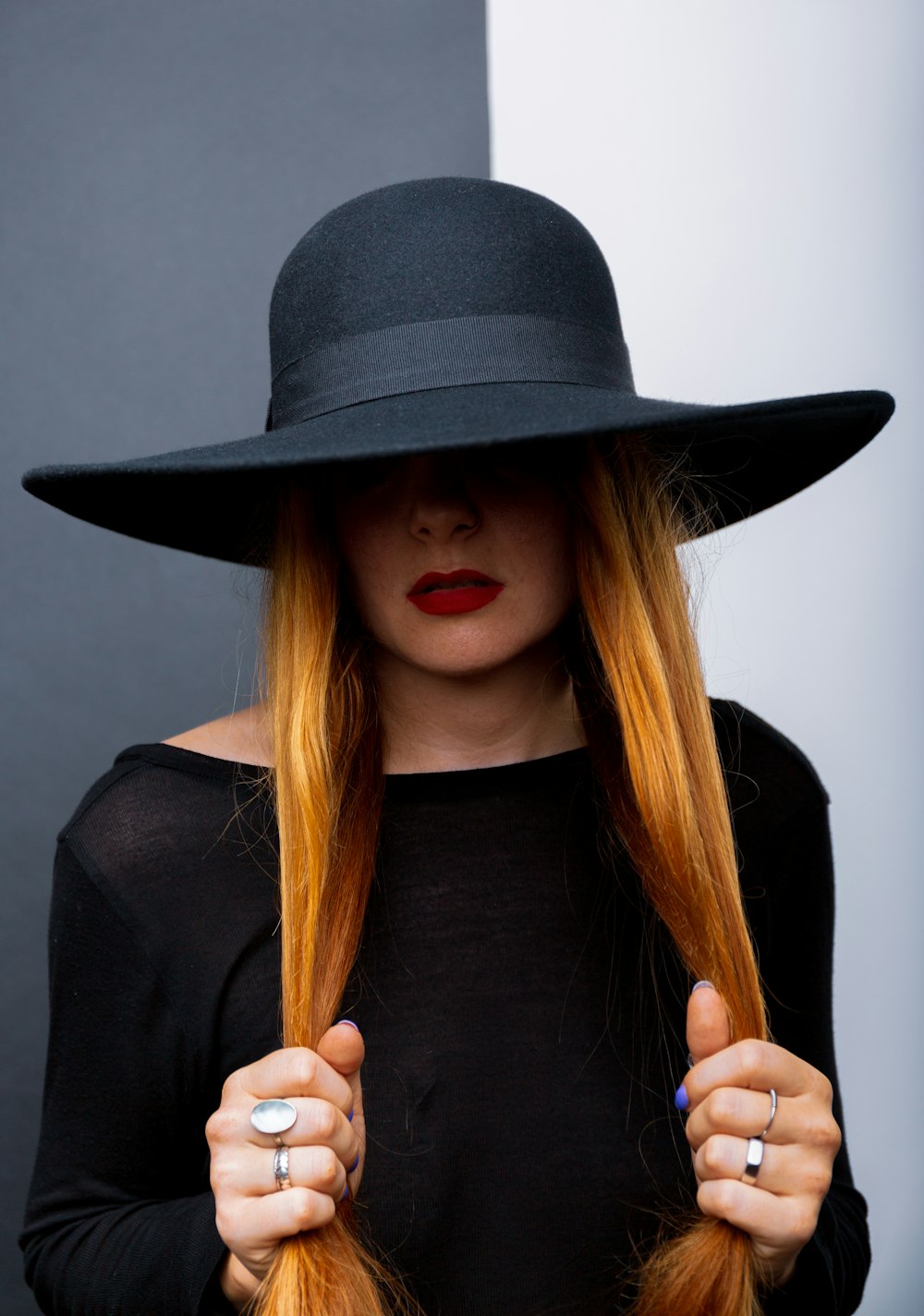a woman with long red hair wearing a black hat