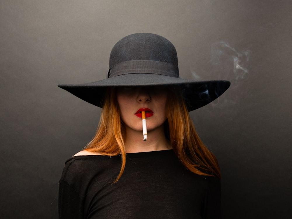 a woman wearing a hat with a cigarette in her mouth
